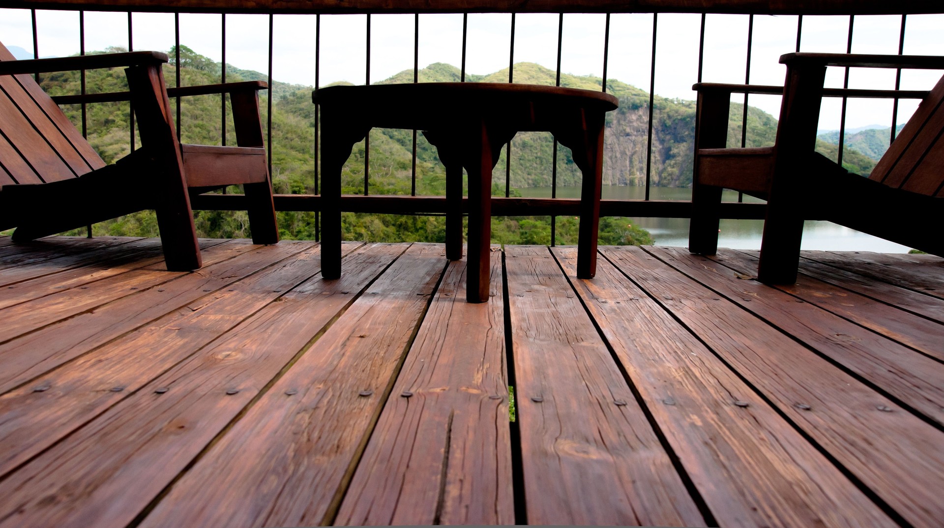 wooden chairs and table in balcony with lush mountain view